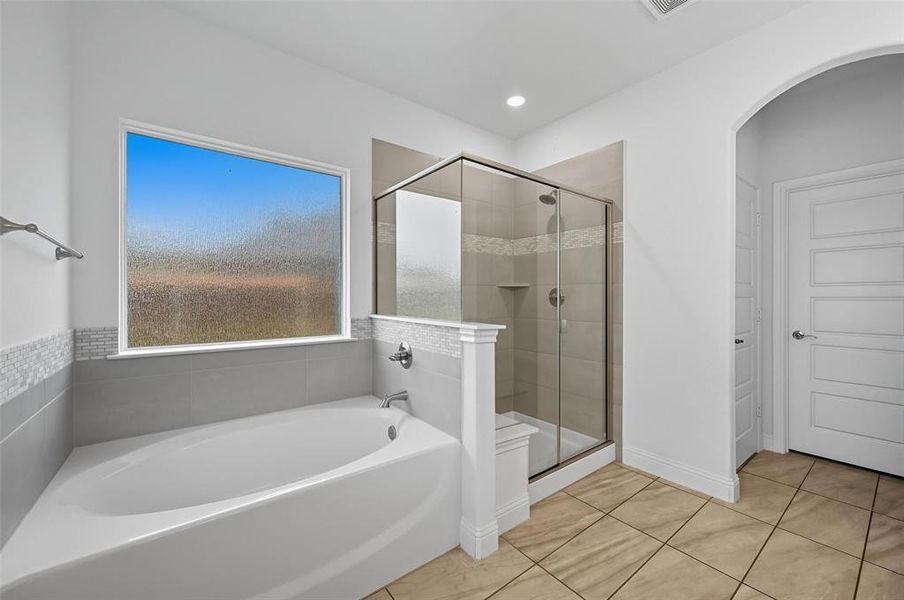Bathroom with a garden tub, a shower stall, and light tile patterned floors