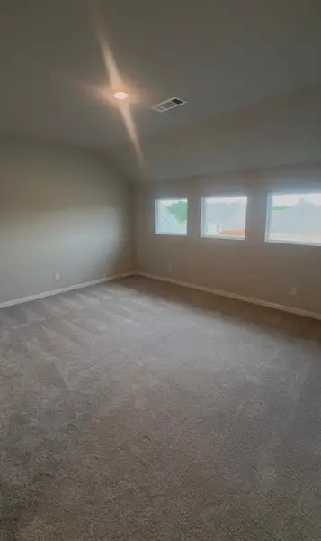 Spacious room featuring neutral carpeting, light neutral wall paint, white trim, recessed ceiling lighting, and a trio of rectangular windows