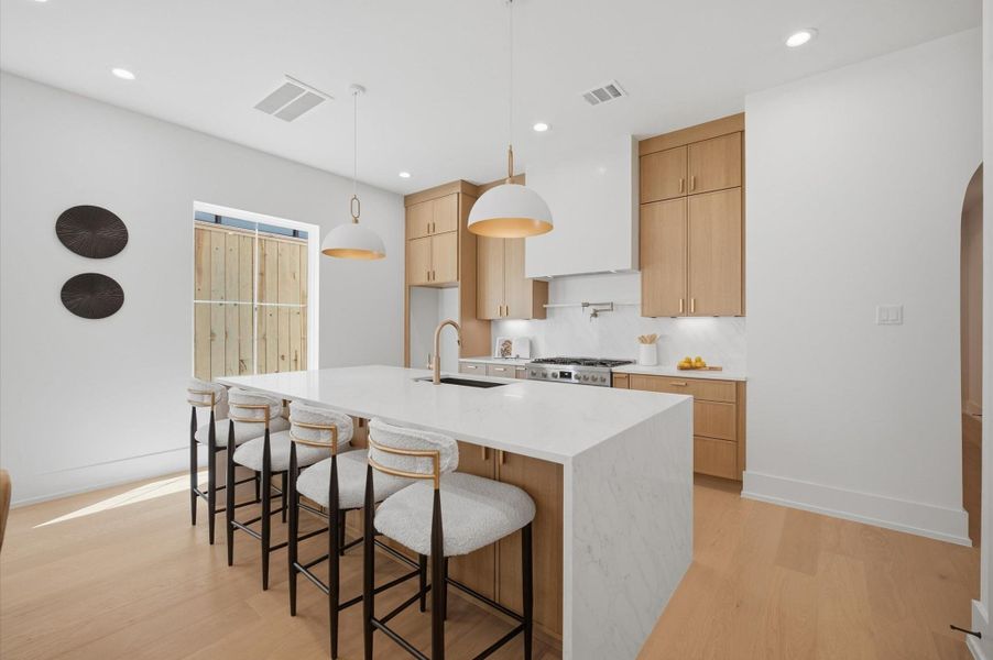 Expansive quartz waterfall island anchors the beautifully appointed kitchen.
