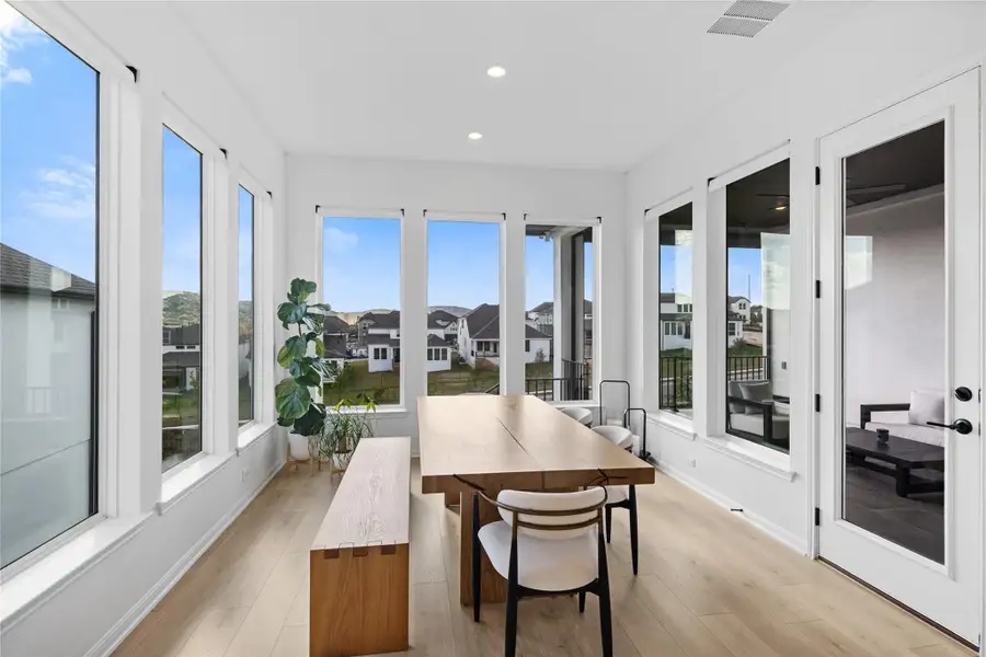 Sunroom with wood finished floors, recessed lighting, and a residential view