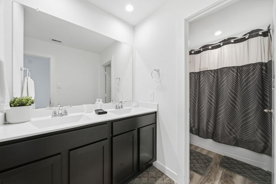 Secondary bathroom featuring a double vanity and a convenient shower-tub combination.