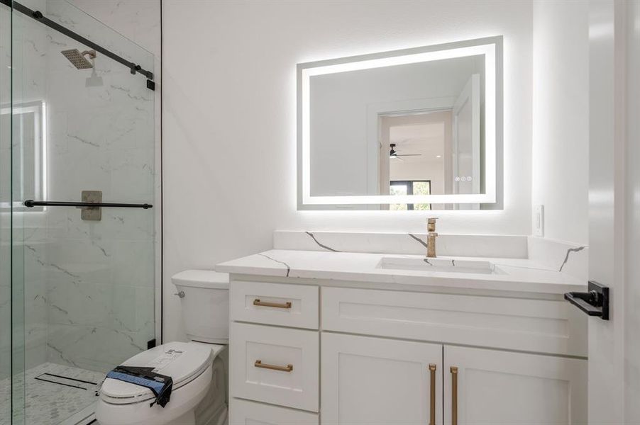 Bathroom with a marble finish shower, vanity, and ceiling fan Bathroom with a marble finish shower, vanity, and ceiling fan