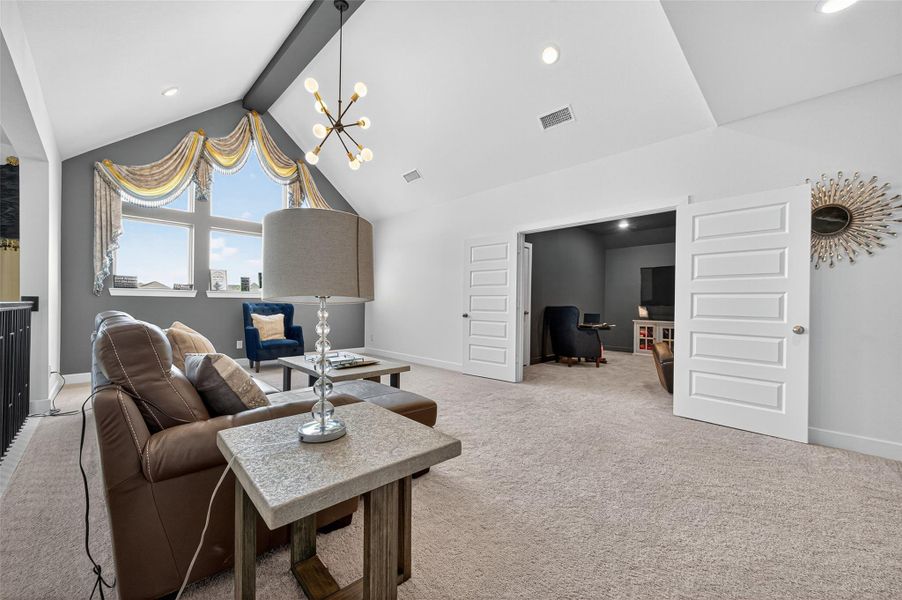 This spacious loft features vaulted ceilings, a modern chandelier, and ample natural light from large windows. It includes a cozy seating area and opens to an adjacent room with double doors, ideal for entertainment or a home office. This spacious loft features vaulted ceilings, a modern chandelier, and ample natural light from large windows. It includes a cozy seating area and opens to an adjacent room with double doors, ideal for entertainment or a home office.