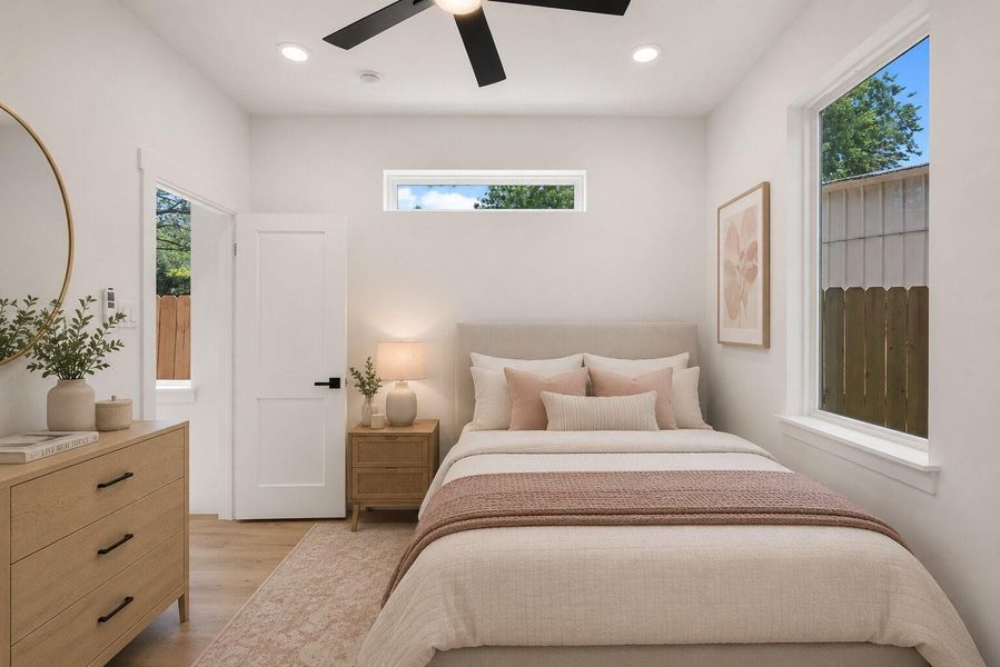 Bedroom retreat suit featuring oversized windows, warm wood-tone flooring and abundant natural light on the first floor
