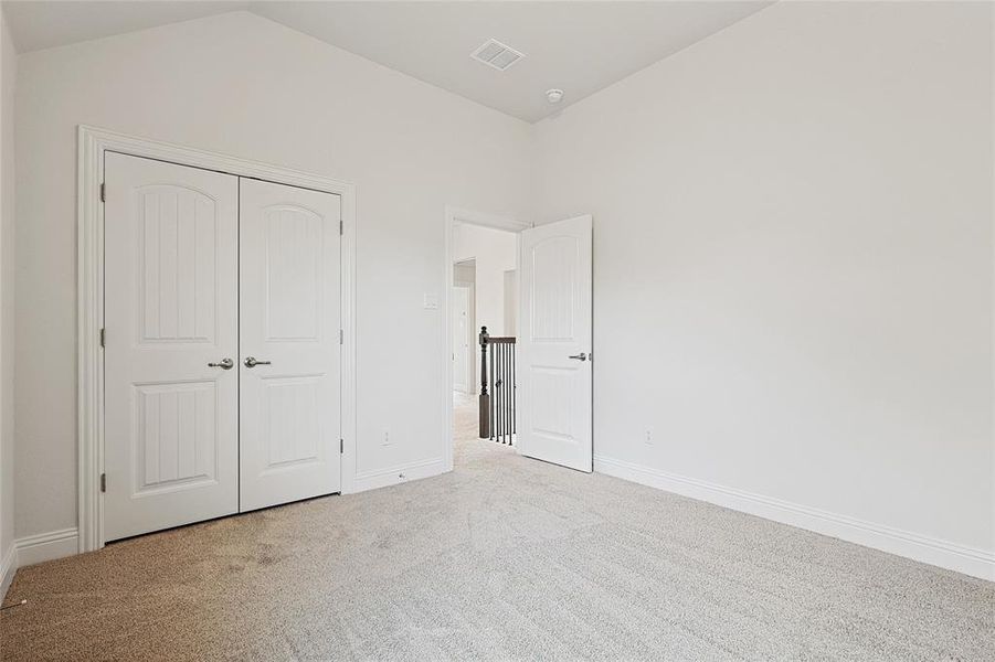 Unfurnished bedroom featuring a closet, carpet floors, and lofted ceiling