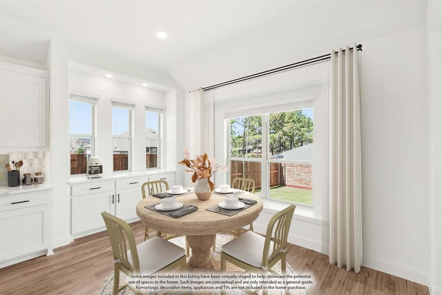 Bright dining area with round wood table, four chairs, hardwood floors, and large windows with white curtains