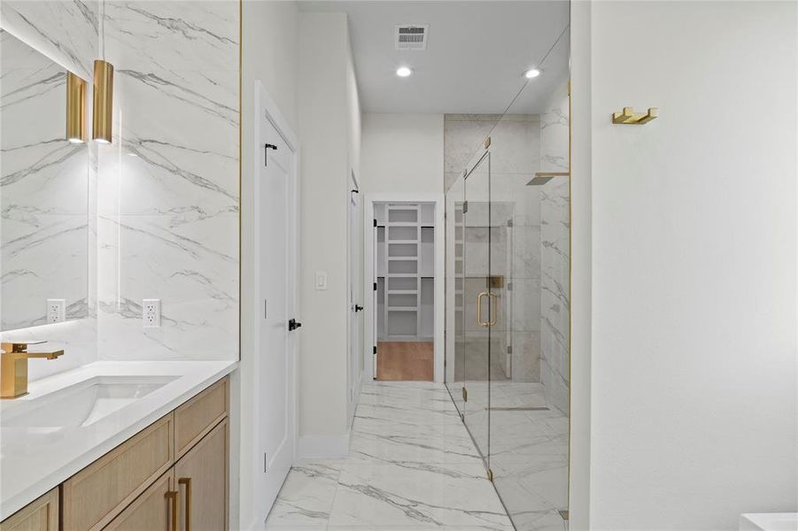 Full bath with marble finish floor, a marble finish shower, visible vents, a spacious closet, and vanity