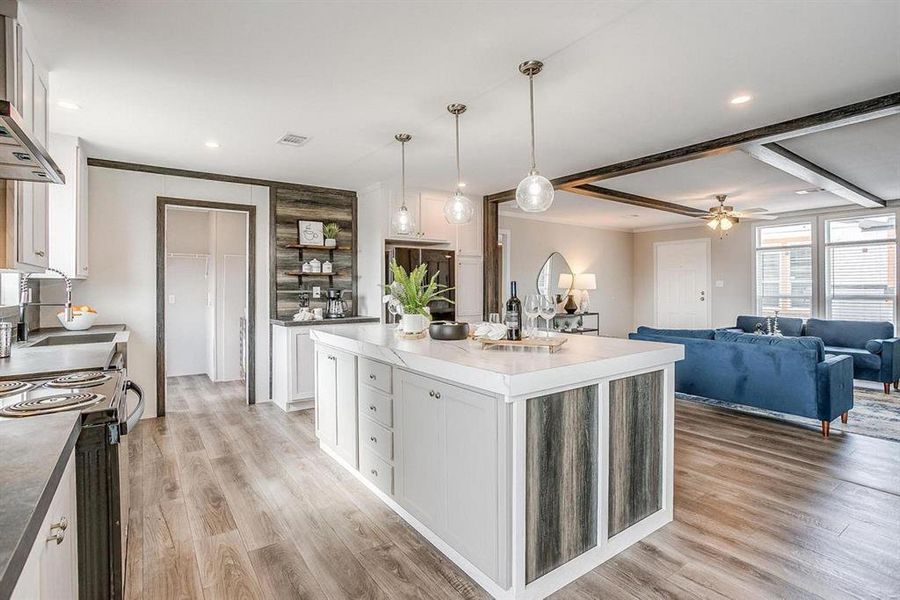 Kitchen featuring pendant lighting, white cabinets, a center island with sink, ceiling fan, and light wood-type flooring