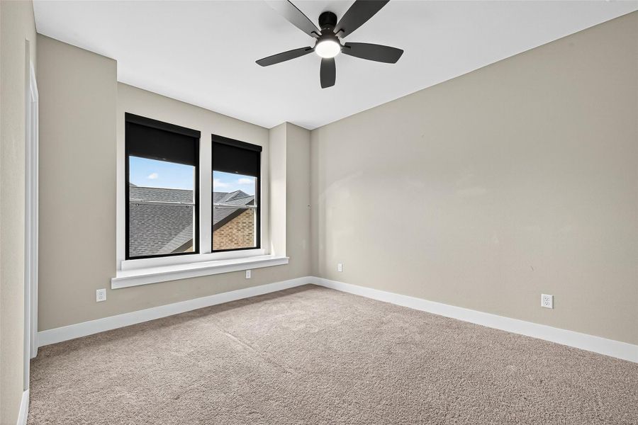 Secondary bedroom 1 upstairs with black out pull down shades and ceiling fan.