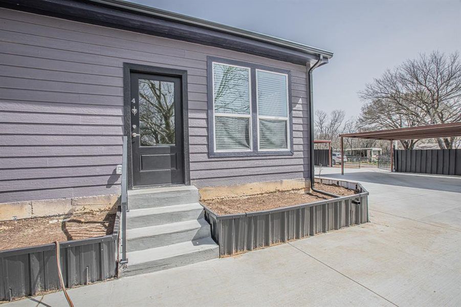 Doorway to property featuring a carport, driveway, and fence