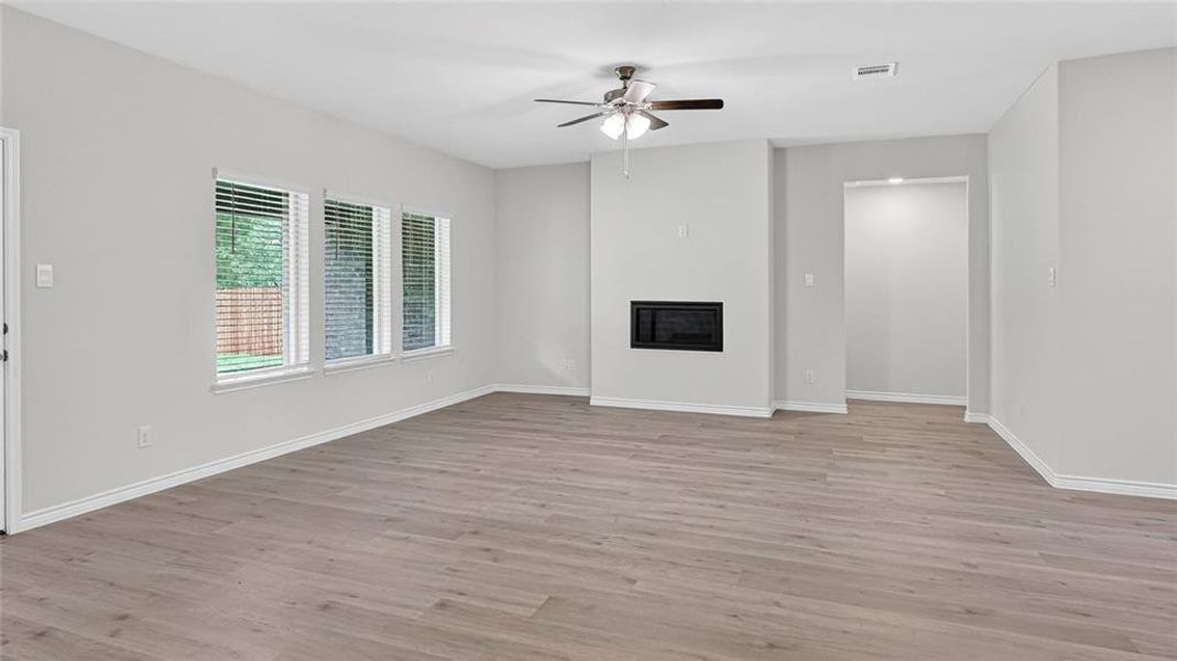 Spacious room featuring wood-finish flooring, light gray wall paint, and white trim