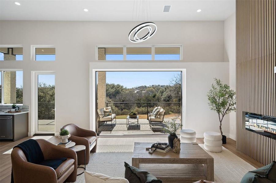 Living room featuring wood finished floors, recessed lighting, plenty of natural light, and a high ceiling Living room featuring wood finished floors, recessed lighting, plenty of natural light, and a high ceiling