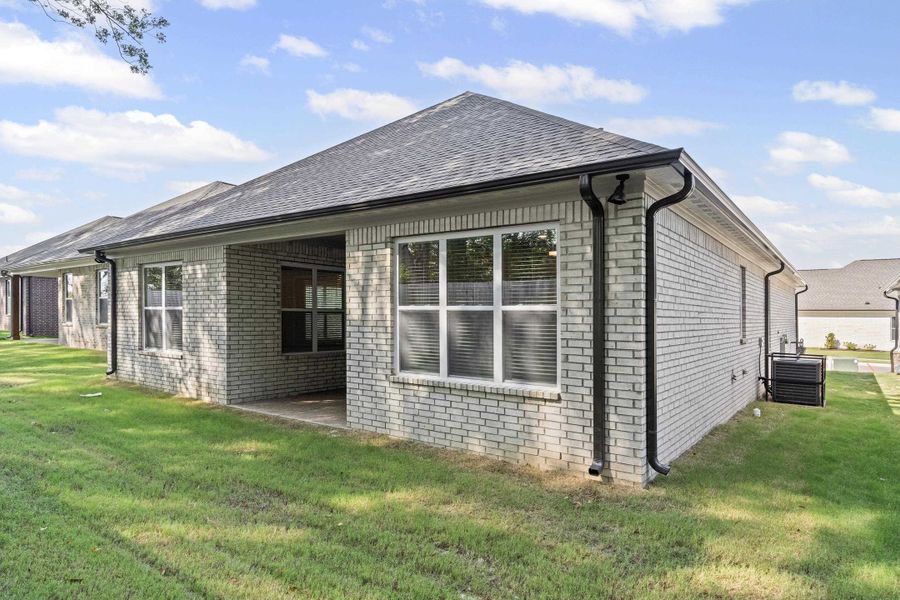 View of home's exterior with a yard, a patio area, brick siding, and a shingled roof