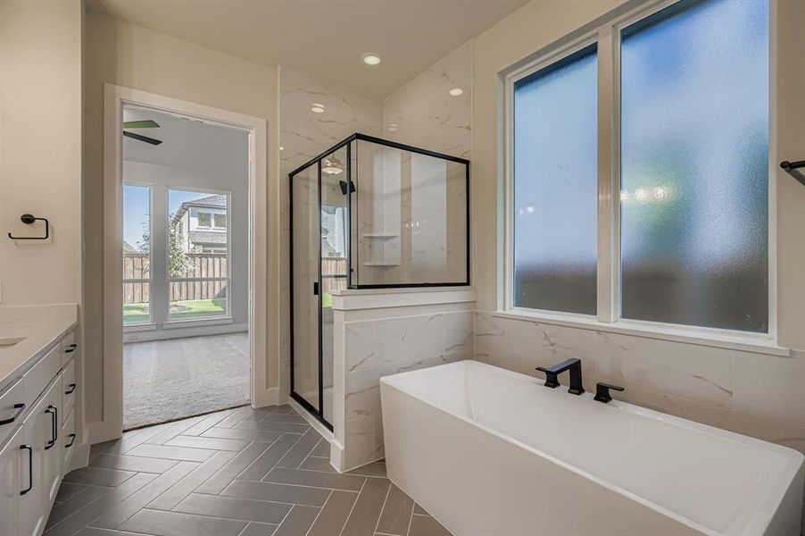 Full bath featuring a freestanding tub, a marble finish shower, vanity, and recessed lighting