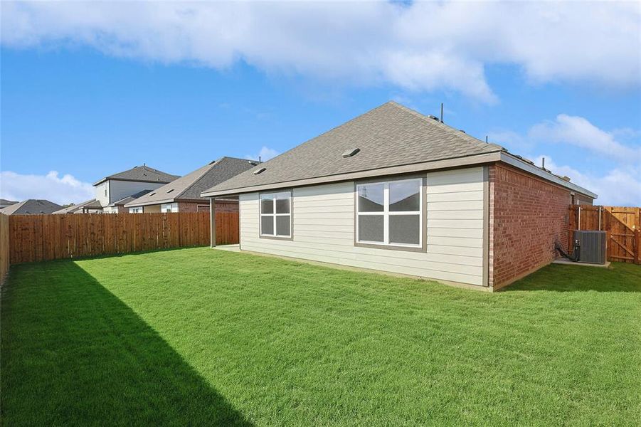 Back of property featuring a lawn and central AC unit