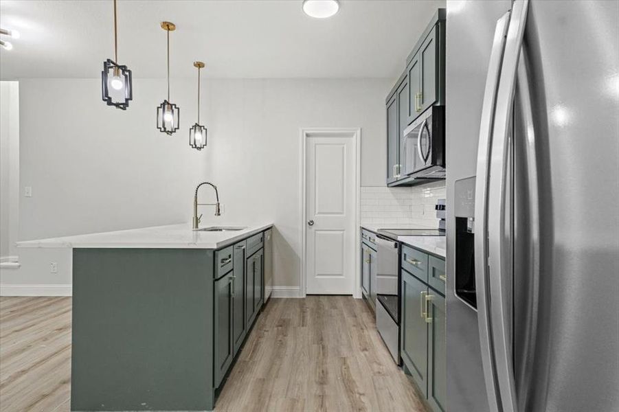 Kitchen with sink, stainless steel appliances, backsplash, kitchen peninsula, and pendant lighting