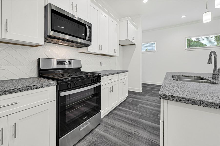 This modern kitchen features white cabinetry, granite countertops, and stainless steel appliances, including a gas stove and built-in microwave. The dark wood flooring complements the bright, open space with ample natural light. This modern kitchen features white cabinetry, granite countertops, and stainless steel appliances, including a gas stove and built-in microwave. The dark wood flooring complements the bright, open space with ample natural light.