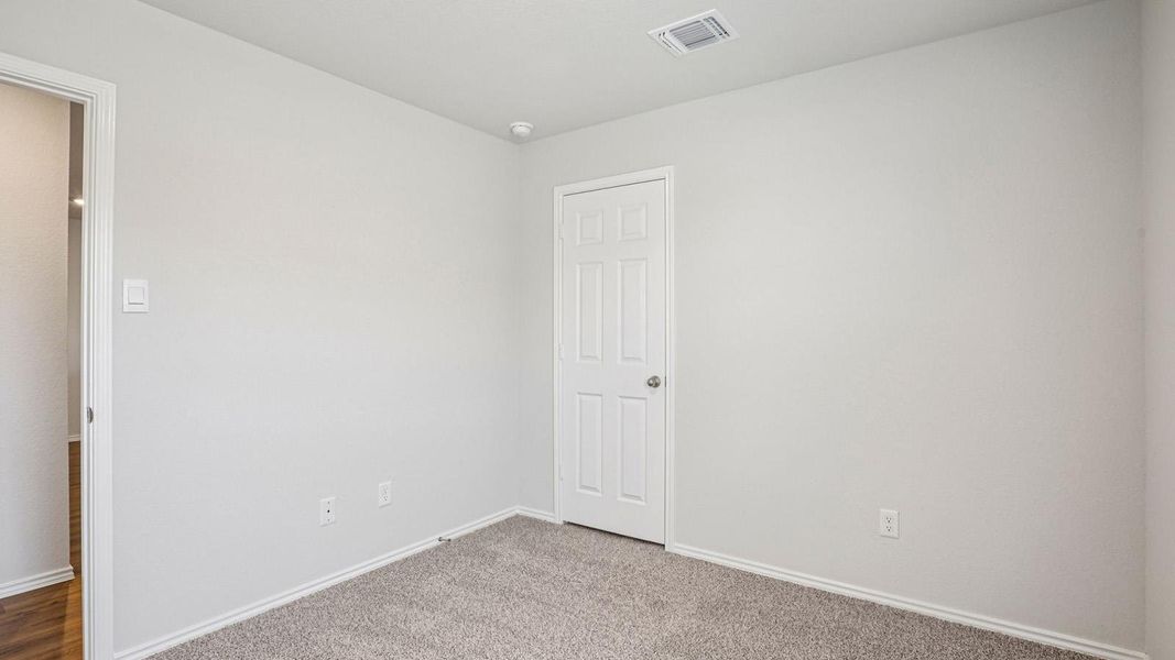Neutral-toned room with plush carpeting, a white paneled door, and a recessed ceiling light Neutral-toned room with plush carpeting, a white paneled door, and a recessed ceiling light