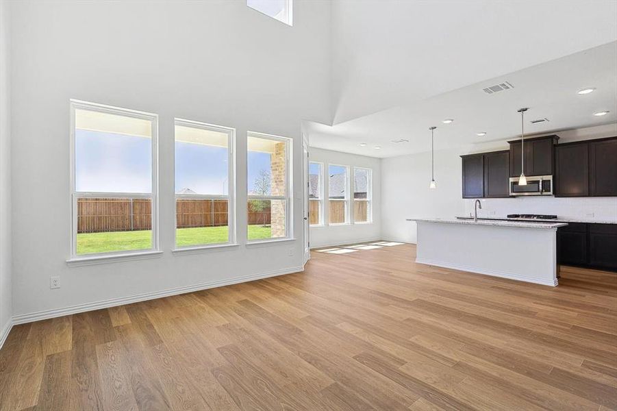 Kitchen featuring pendant lighting, sink, dark brown cabinetry, and light wood-type flooring