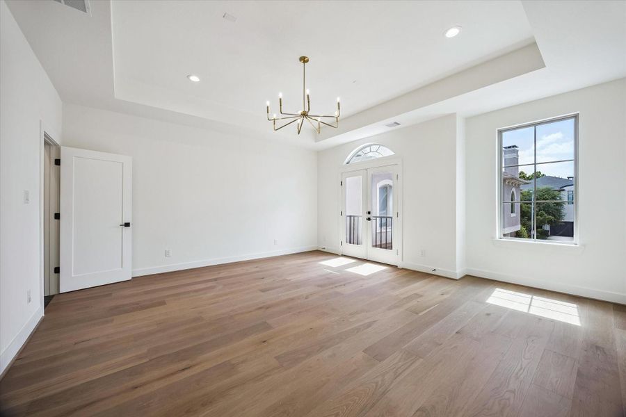 Step into the serene primary suite, where an elegant tray ceiling and abundant natural light highlight the rich floors. French doors open to a charming Juliet balcony overlooking the peaceful, gated community, quietly nestled within one of the Museum District's most desirable neighborhoods.