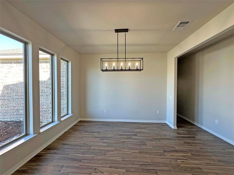 Unfurnished dining area with dark wood-type flooring and a chandelier Unfurnished dining area with dark wood-type flooring and a chandelier