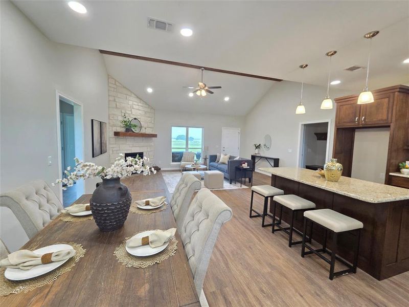 Dining space with a stone fireplace, light wood-style floors, ceiling fan, high vaulted ceiling, and recessed lighting Dining space with a stone fireplace, light wood-style floors, ceiling fan, high vaulted ceiling, and recessed lighting