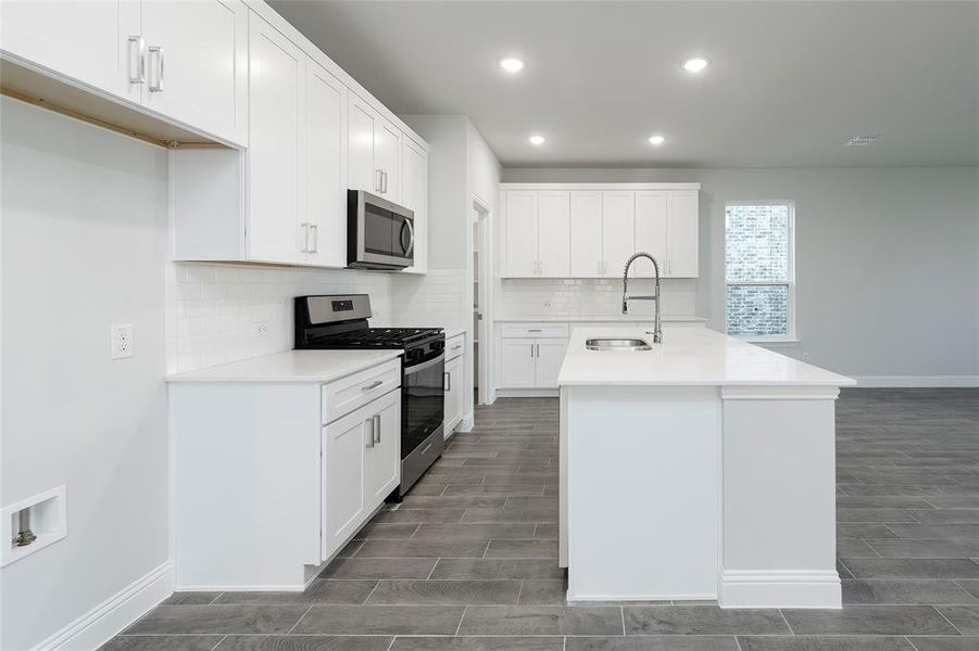 Kitchen with stainless steel appliances, a sink, wood finish floors, baseboards, and recessed lighting Kitchen with stainless steel appliances, a sink, wood finish floors, baseboards, and recessed lighting