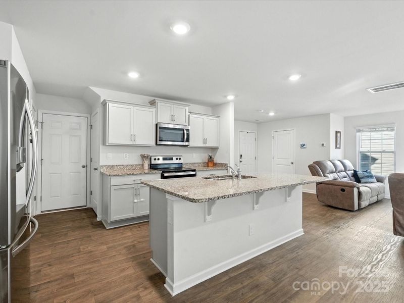 Large kitchen island with granite countertops serves as centerpiece for this open-concept floor plan. Ample cabinet storage and counter space make this kitchen both beautiful and highly functional.