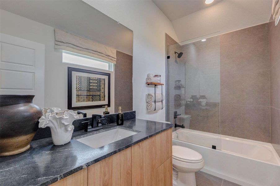 This well-appointed bathroom features a sleek vanity, modern fixtures, and a combination tub and shower for added versatility. Neutral finishes create a timeless look, while thoughtful design ensures both comfort and functionality. Perfect for guests or family use, this space offers everything needed for everyday living. The picture shown is from the model home with the same floor plan, Rev floor plan.