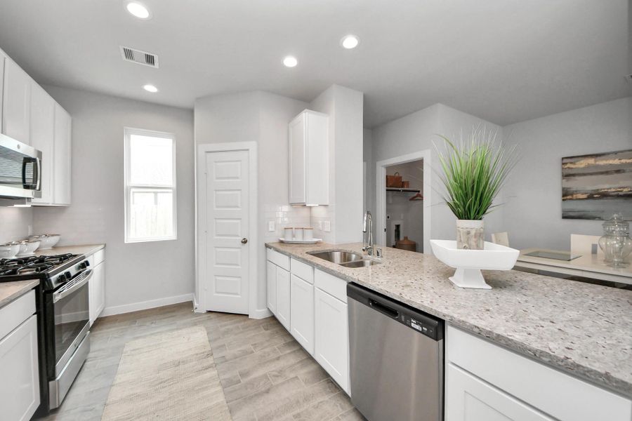 The kitchen is a culinary haven, featuring granite countertops, a tile backsplash, stainless steel appliances, 42” upper cabinets, and undercabinet lighting. Sample photo of completed home with similar floor plan. Actual colors and selections may vary.