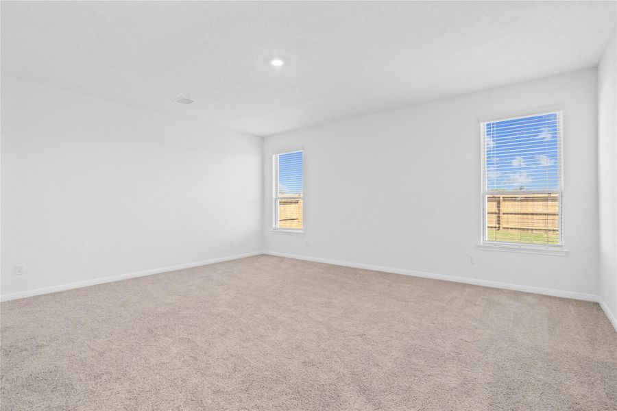 Unwind after a long day in this stunning primary suite! This spacious retreat features plush carpeting, warm-toned walls, soaring ceilings, recessed lighting, and large windows with privacy blinds for comfort and tranquility.