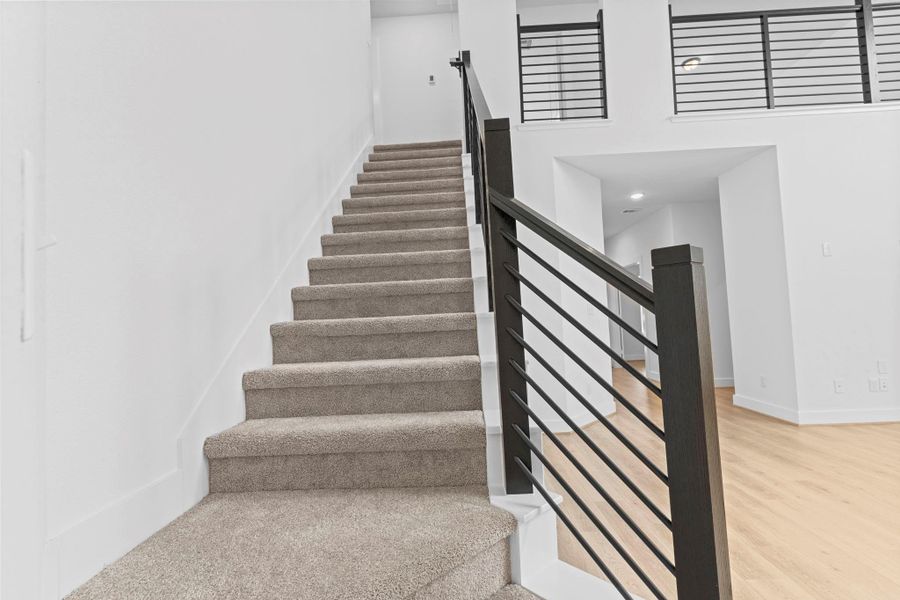 A view of the staircase leading to the second floor showcases the modern wrought iron railing and soft carpeted steps, offering both safety and style with a contemporary finish. **Image Representative of Plan Only and May Vary as Built**.