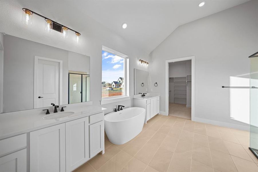 Full bathroom with a spacious closet, a soaking tub, vaulted ceiling, a shower stall, and two vanities Full bathroom with a spacious closet, a soaking tub, vaulted ceiling, a shower stall, and two vanities