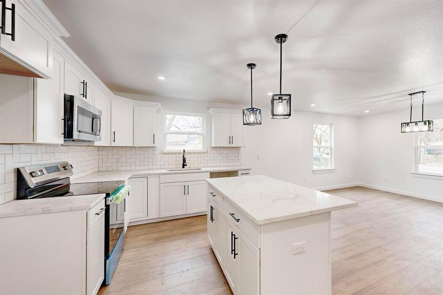 Kitchen with sink, a kitchen island, a healthy amount of sunlight, and appliances with stainless steel finishes