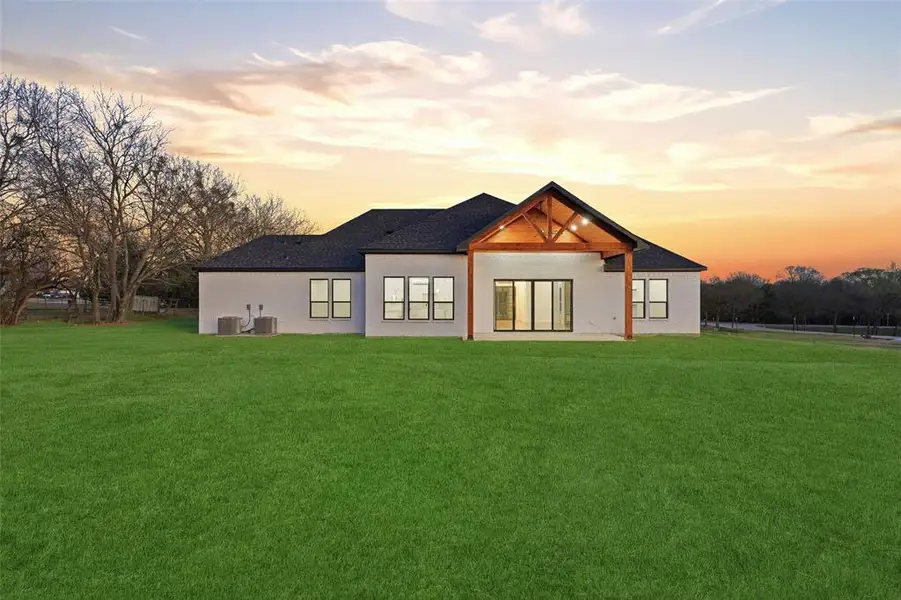 Back of property at dusk with a patio area and a yard