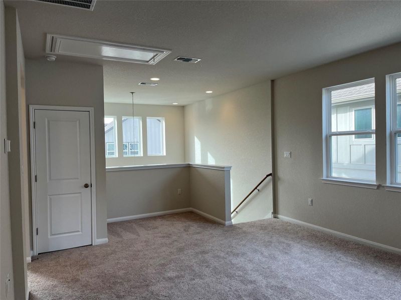 Empty room with attic access, plenty of natural light, light carpet, and a textured ceiling Empty room with attic access, plenty of natural light, light carpet, and a textured ceiling