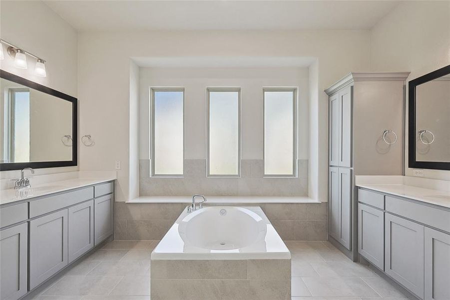 Bathroom with tile patterned floors, a relaxing tiled tub, and vanity