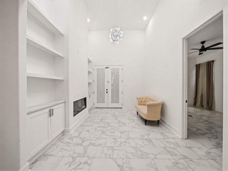 Family room: ceramic tile flooring, decreative electric fireplace, both cabinets and shelving, decreative ceiling light fixture, and 8 ft. doors leading out to the patio