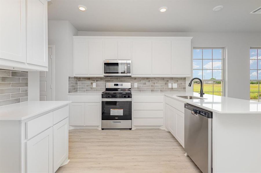 Kitchen with appliances with stainless steel finishes, decorative backsplash, recessed lighting, and light countertops