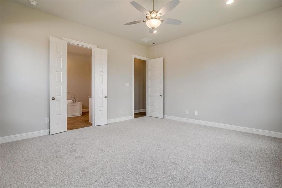 Unfurnished bedroom featuring carpet floors, ensuite bath, and ceiling fan