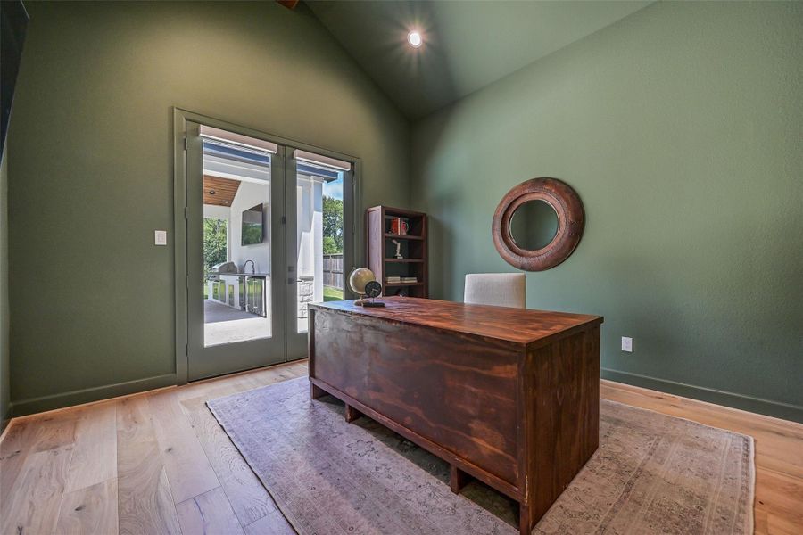 Private first-floor study features a dramatic vaulted ceiling, rich accent walls, wood flooring & French doors opening to the covered patio, plus a closet that allows this versatile space to function as a potential 7th bedroom.