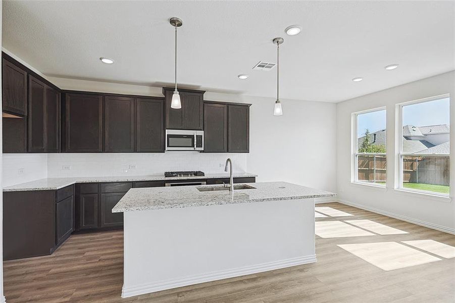 Kitchen featuring light hardwood / wood-style flooring, stainless steel appliances, sink, and decorative light fixtures