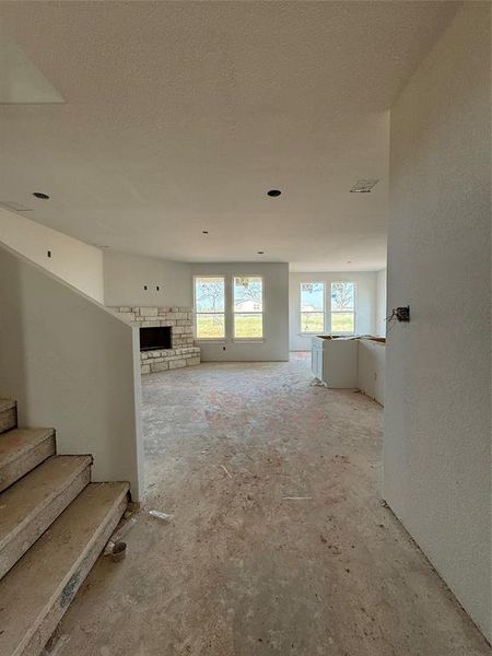 Living room with visible vents, a textured ceiling, a fireplace, and stairs