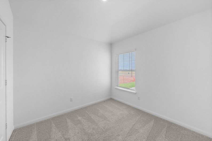 A single window provides natural light to this carpeted bedroom space.