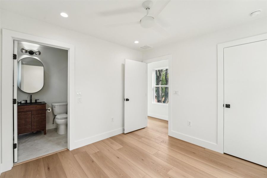 Bedroom with baseboards, light wood finished floors, connected bathroom, recessed lighting, and ceiling fan