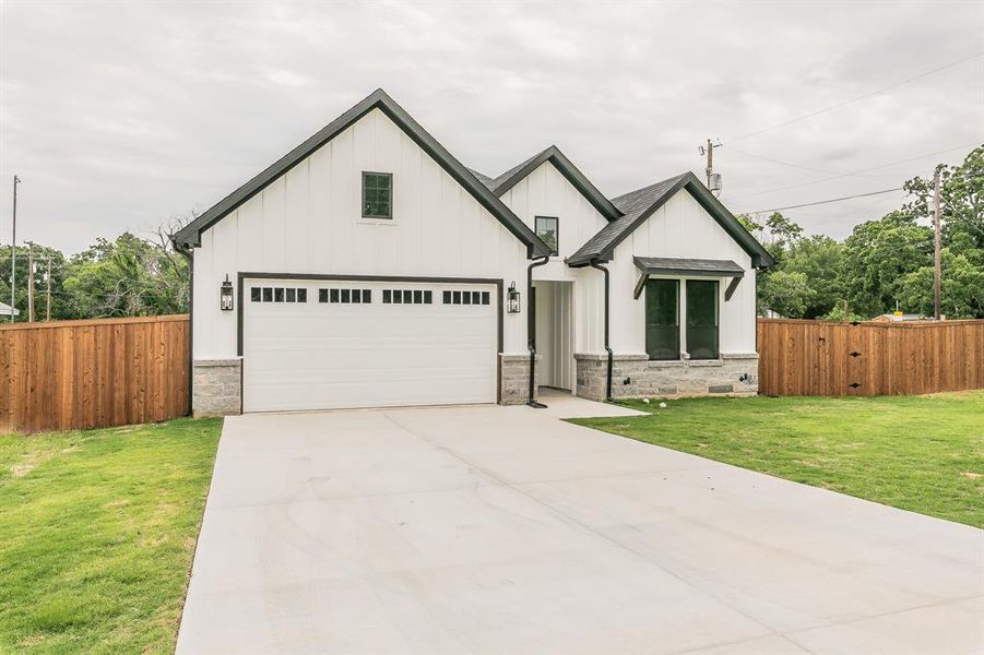 Modern farmhouse featuring board and batten siding, driveway, a garage, and stone siding Modern farmhouse featuring board and batten siding, driveway, a garage, and stone siding