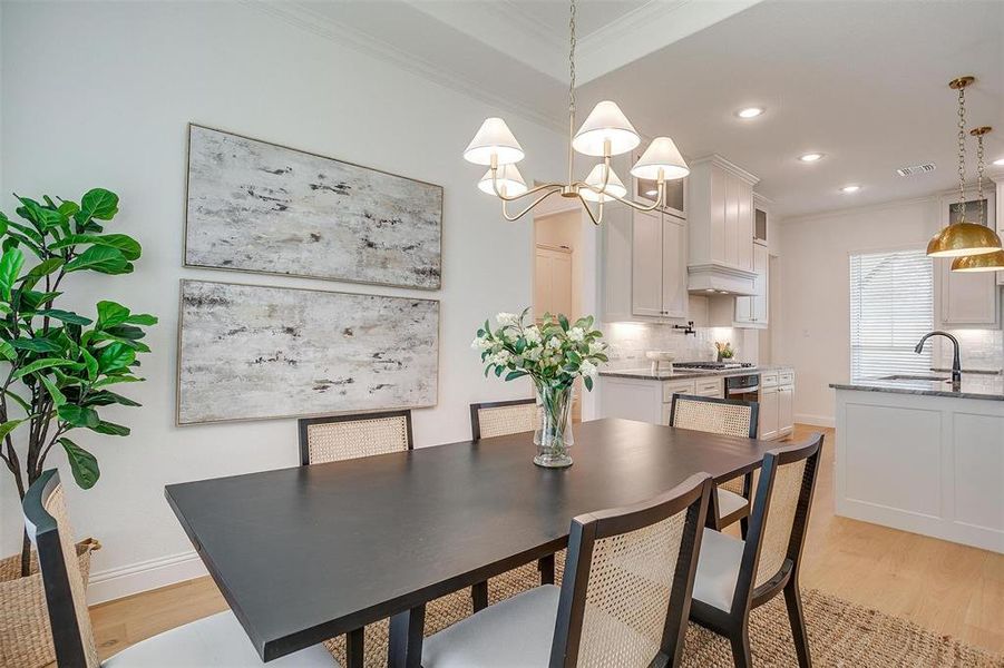 Dining space featuring ornamental molding, sink, light hardwood / wood-style flooring, and a chandelier