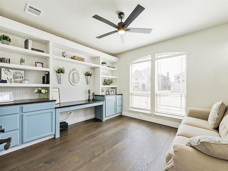 Office featuring built in desk, ceiling fan, and dark hardwood / wood-style flooring