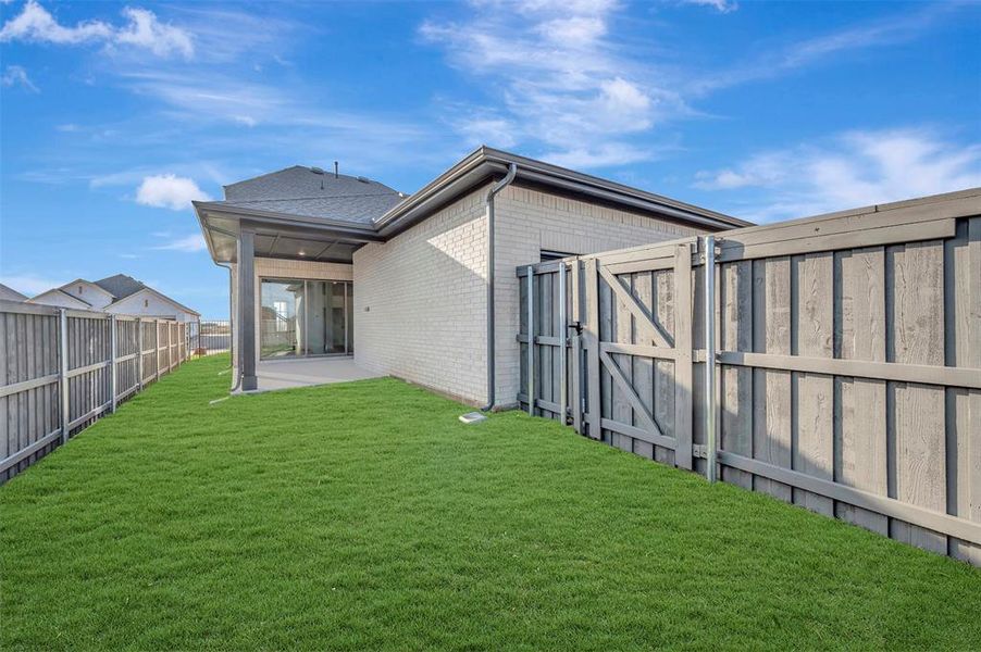 Back of house with a gate, a fenced backyard, brick siding, and a patio area Back of house with a gate, a fenced backyard, brick siding, and a patio area