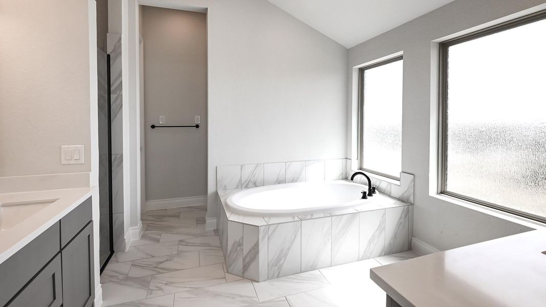Bathroom featuring vanity, lofted ceiling, baseboards, marble finish floor, and a garden tub Bathroom featuring vanity, lofted ceiling, baseboards, marble finish floor, and a garden tub